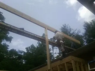 Carpenter setting a ridge beam over a new addition frame in Calhan