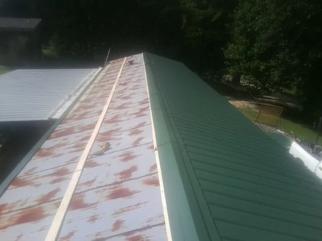 Old rusted panels beside newly installed green metal roofing — Wind Damage Roof Repair by Roofing Brothers in Calhan