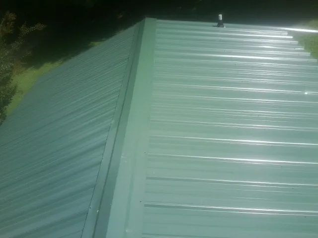 New green metal panels meeting at the ridge of a roof — Flat Roof Repair work by our crew in Calhan