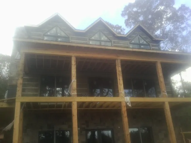 Dormers and porch framing on a large log home under construction — Roof Coating work by our crew in Calhan