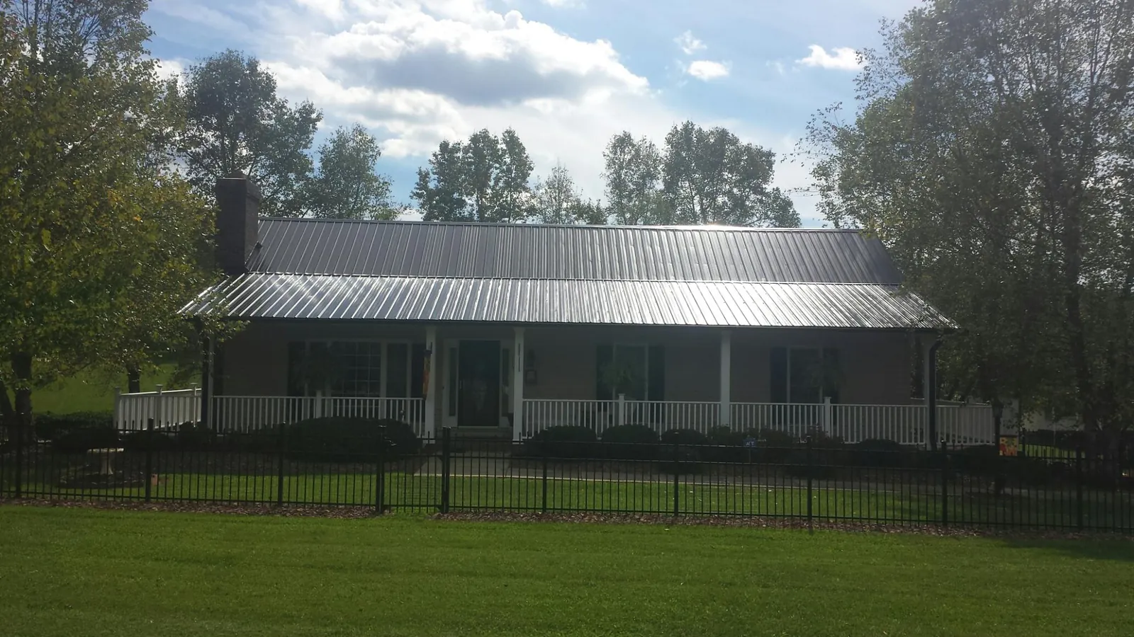 Gray metal roof on a brick ranch with a full width front porch — Gutter Guard Installation work by our crew in Calhan