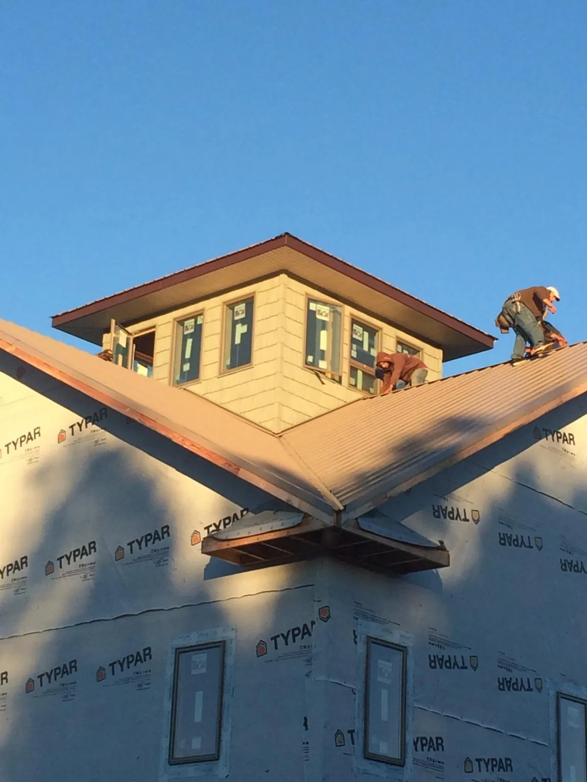 Roofers working around a rooftop cupola on a new metal roof at sunset — Roof Waterproofing in Calhan by Roofing Brothers